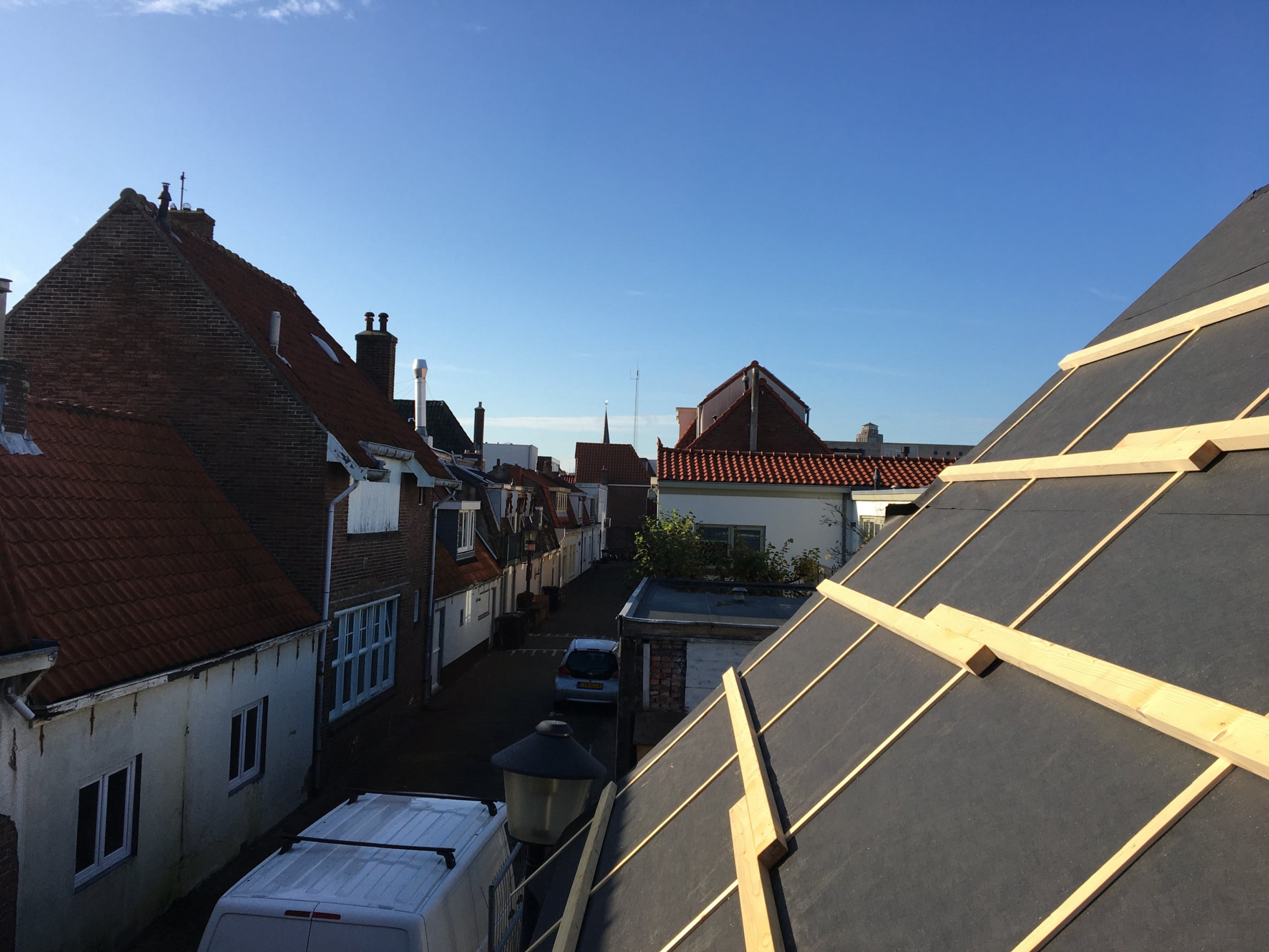 Constructie van een dakopbouw door DHB Bouw B.V. op een zonnige dag in Zandvoort, met vakmanschap in houtwerk en dakbedekking zichtbaar tegen de achtergrond van traditionele Nederlandse huizen.